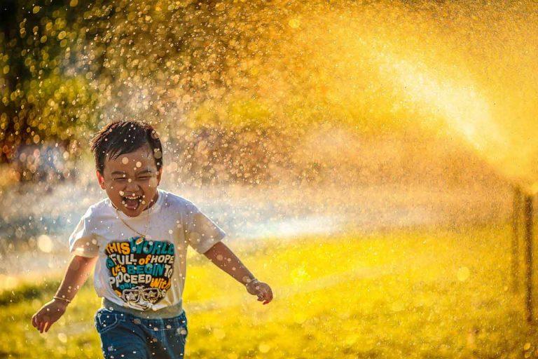 Outdoor Summer Activities For Kids - Kids Running Through A Sprinkler